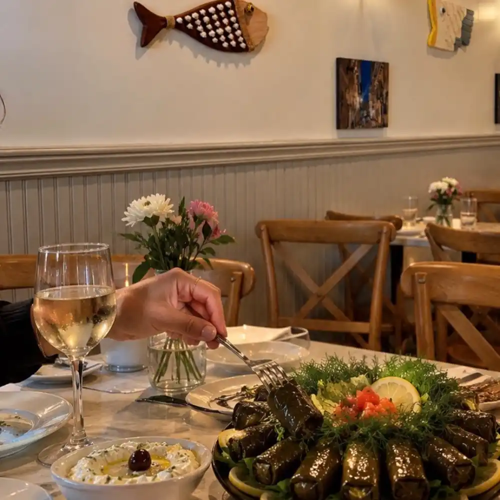 A platter of dolmathes on a table set with wine glasses and flowers