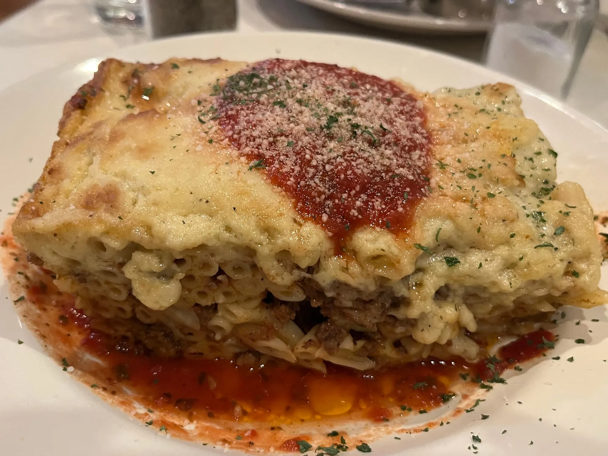 A square of pastitsio with a thick bechamel top and tomato sauce
