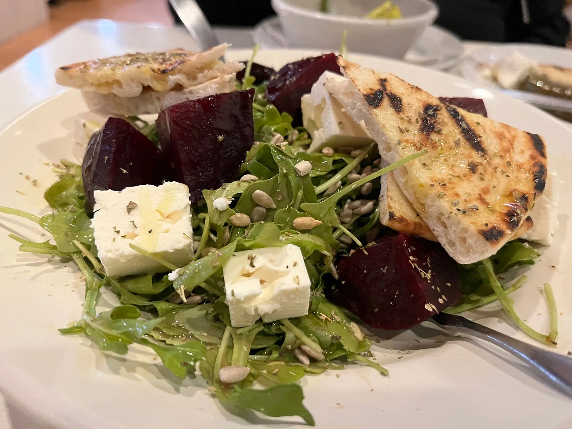 Piato salad with beets, arugula, feta, sunflower seeds and grilled pita